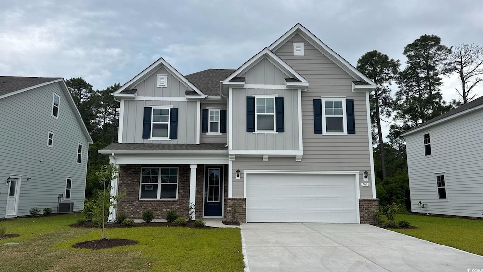 Craftsman-style house with board and batten siding, brick siding, a front yard, and driveway