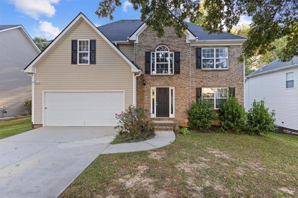 View of front of property with concrete driveway, a front yard, an attached garage, and brick siding