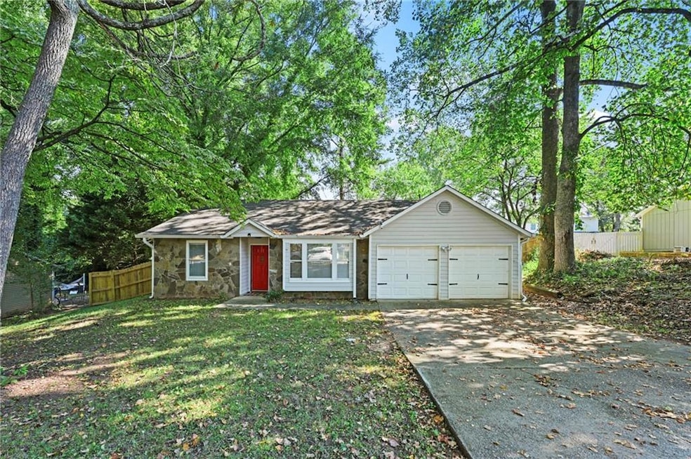 View of front of home featuring an attached garage, concrete driveway, and stone siding