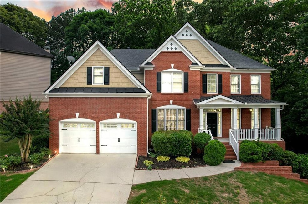 View of front of house with a porch, brick siding, an attached garage, driveway, and a standing seam roof