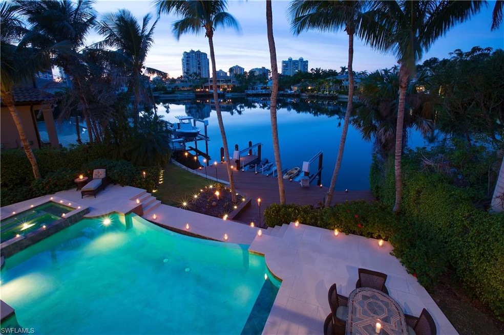 Pool at dusk featuring a water view, a patio area,