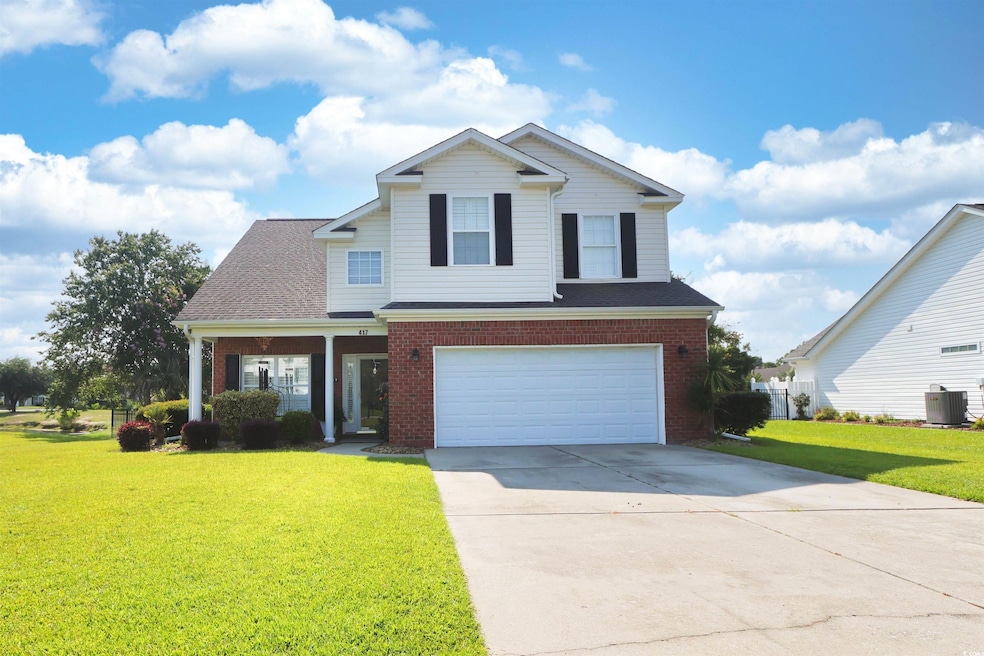 Traditional home featuring brick siding, a garage, a front lawn, and driveway