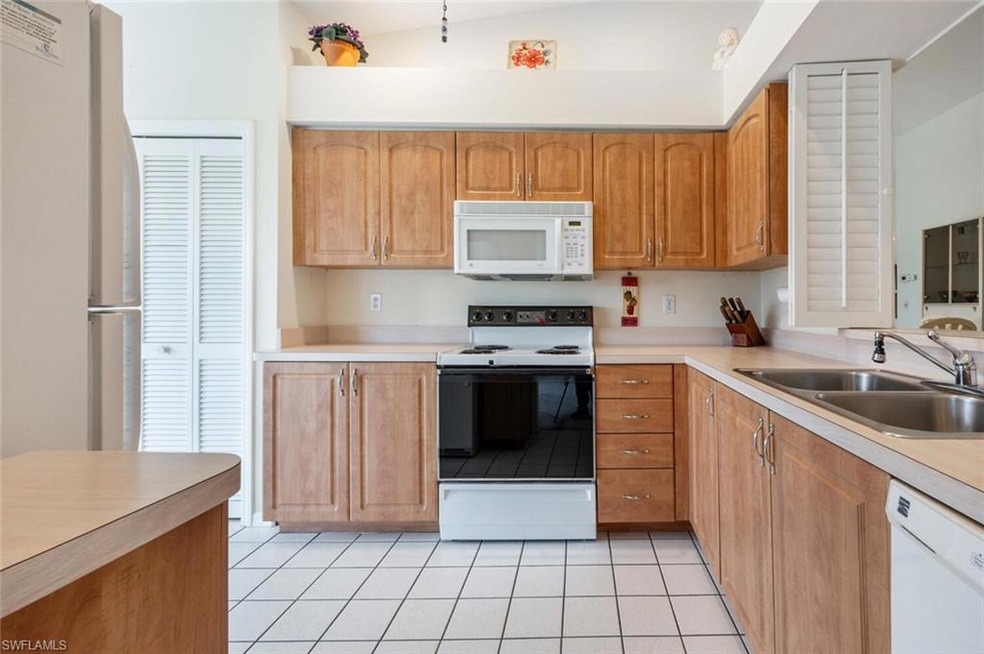 Kitchen with light tile patterned floors, white ap