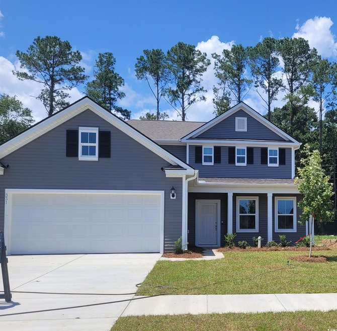 Traditional-style house with driveway, a front yard, and a garage