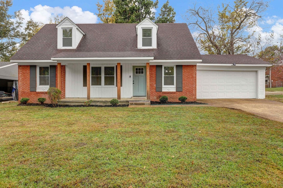 Cape cod-style house featuring covered porch, a shingled roof, a front yard, driveway, and brick siding