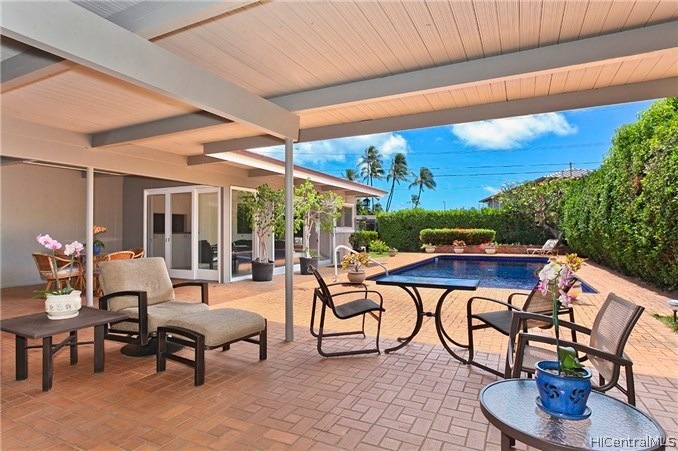 Expansive covered lanai leads to a large tiled poo
