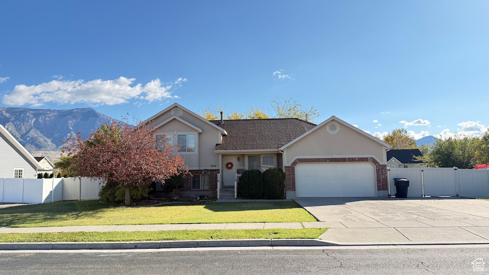 View of front of home featuring concrete driveway, stucco siding, a garage, brick siding, and a gate