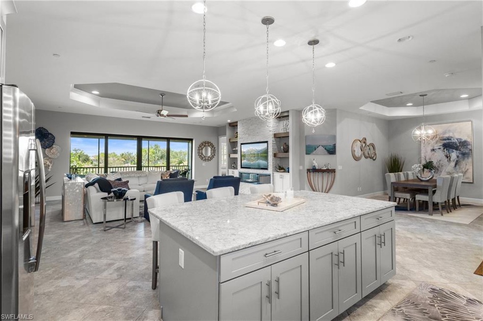 Kitchen featuring a tray ceiling, recessed lighting, a chandelier, a ceiling fan, and open floor plan