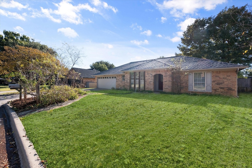 Single story home with a front yard, an attached garage, brick siding, and driveway
