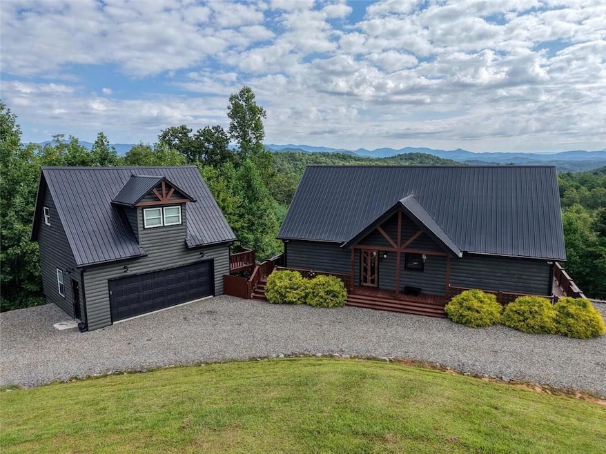 View of front of property featuring a deck with mountain view, a metal roof, a front yard, and driveway