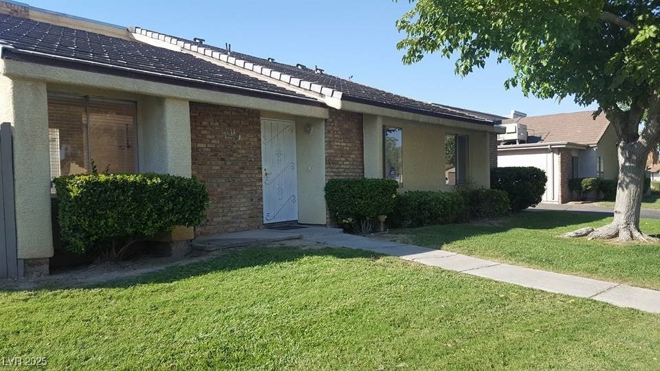 Entrance to property featuring a yard, brick siding, and stucco siding