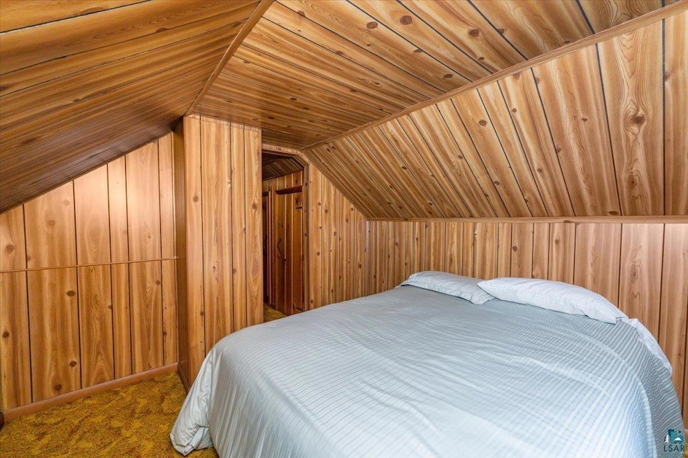 Bedroom with wooden walls, wood ceiling, vaulted ceiling, and carpet flooring