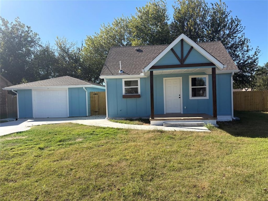 View of front of home with board and batten siding, a porch, an outdoor structure, and roof with shingles