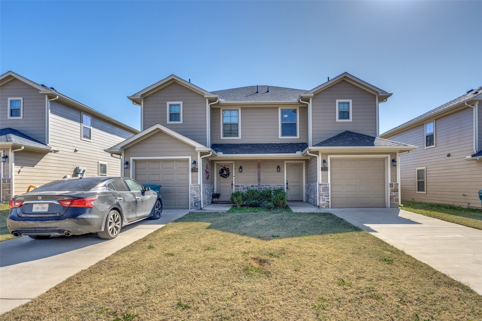 Traditional home with roof with shingles, concrete driveway, a front lawn, stone siding, and covered porch