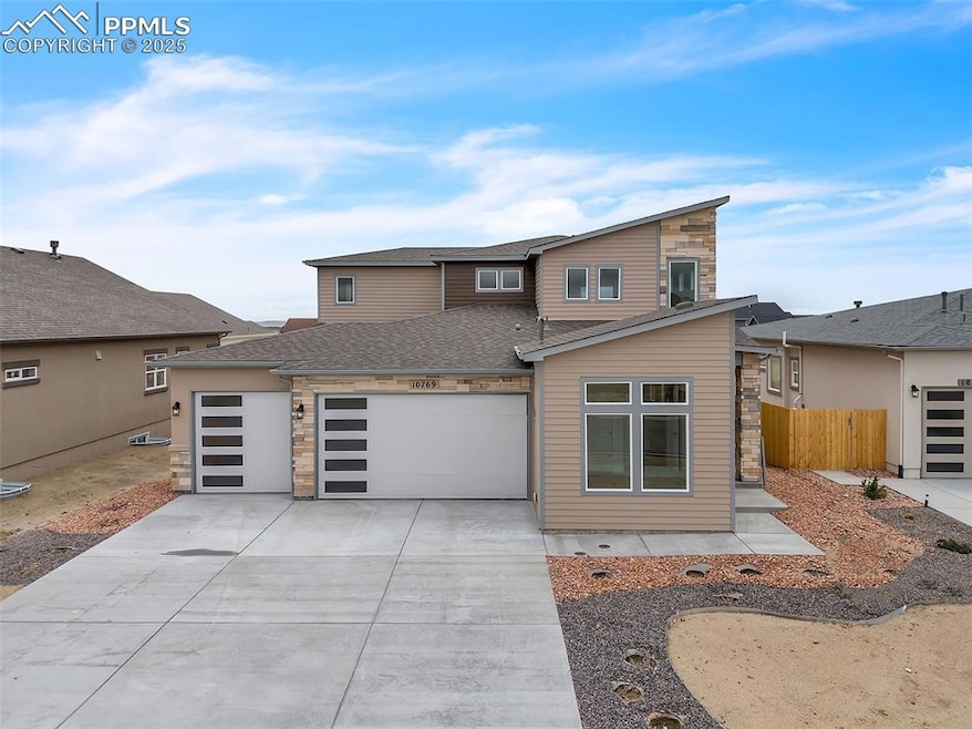 View of front of property with an attached garage, concrete driveway, stone siding, and a shingled roof