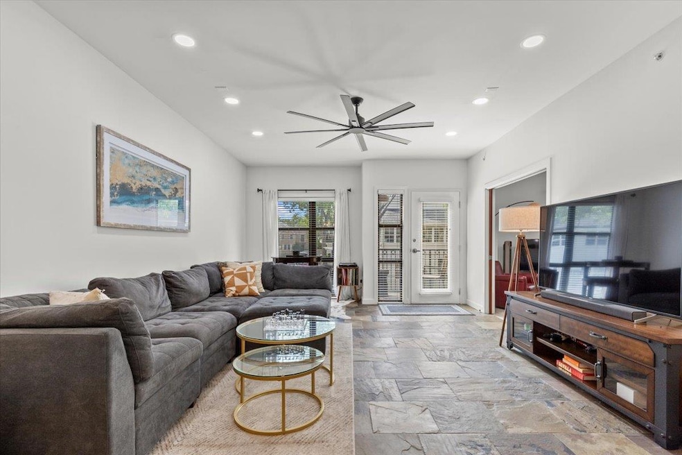 Living room with recessed lighting, stone tile floors, ceiling fan, and baseboards