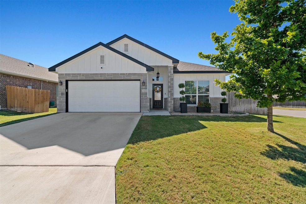 Modern farmhouse featuring board and batten siding, concrete driveway, an attached garage, and stone siding