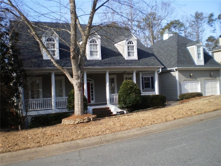 Cape cod-style house featuring a porch, a garage, a chimney, and roof with shingles