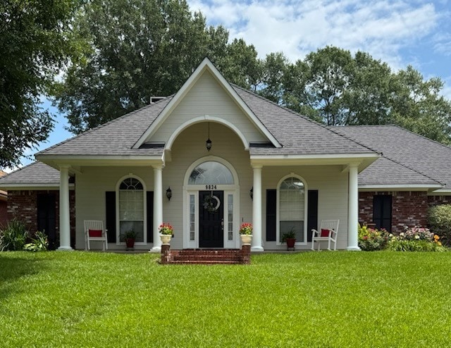 View of front of house featuring a porch, a front lawn, and a shingled roof