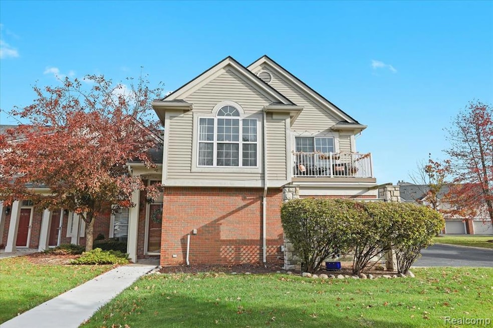 View of front of property with a balcony, a front lawn, and brick siding