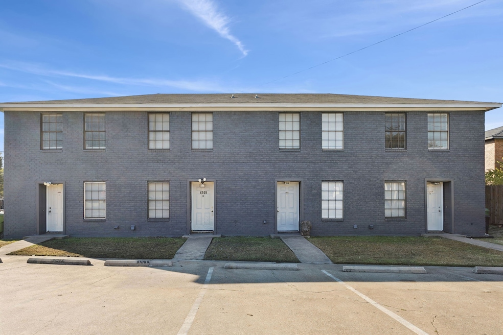 Colonial home with uncovered parking and brick siding