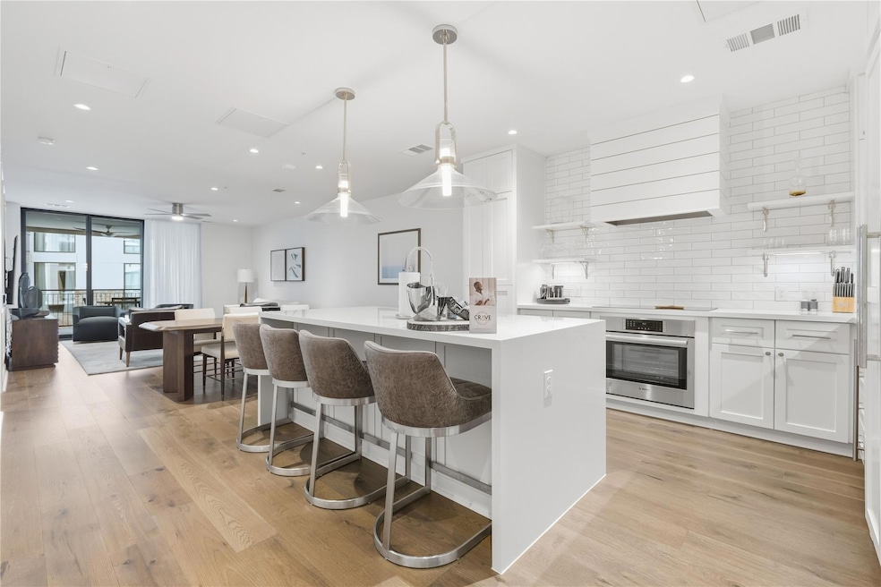 Kitchen with white cabinets, decorative light fixtures, open shelves, open floor plan, and tasteful backsplash