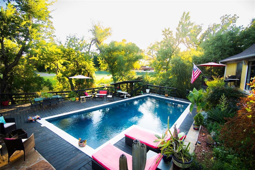 View of pool featuring a wooden deck and outdoor dining area