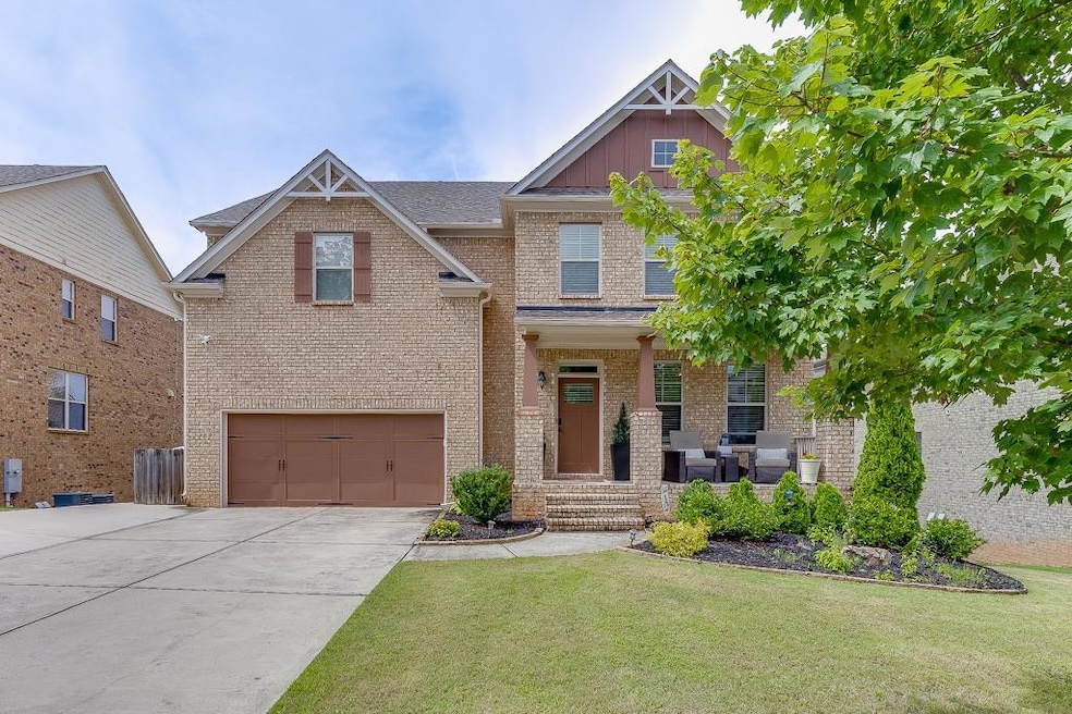 Craftsman inspired home with brick siding, a garage, driveway, and a front lawn