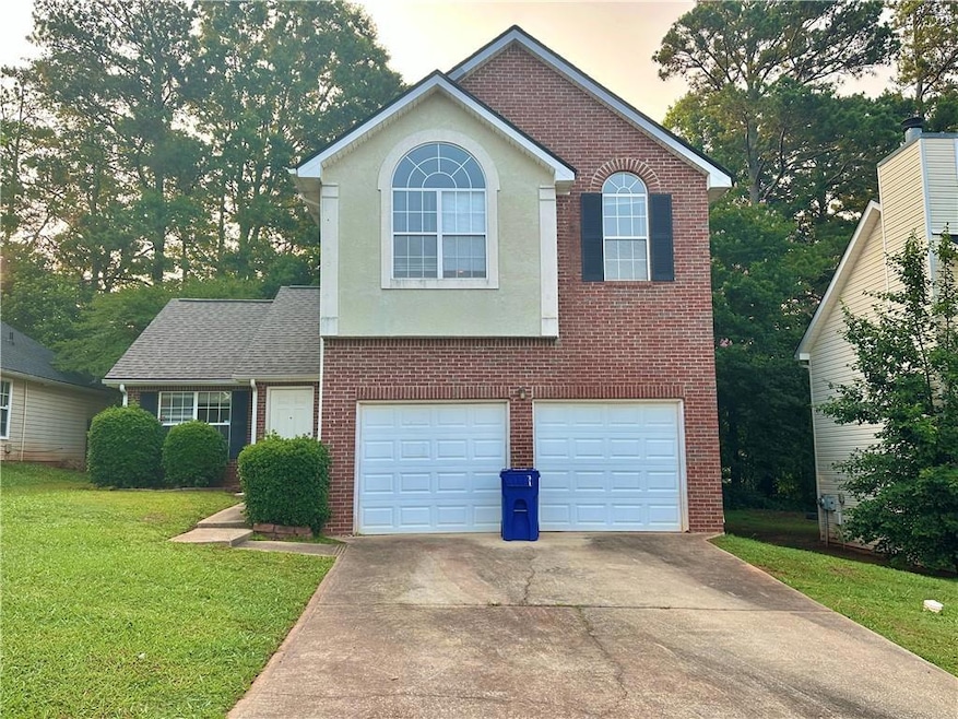 View of front of property featuring concrete driveway, an attached garage, brick siding, and a front yard