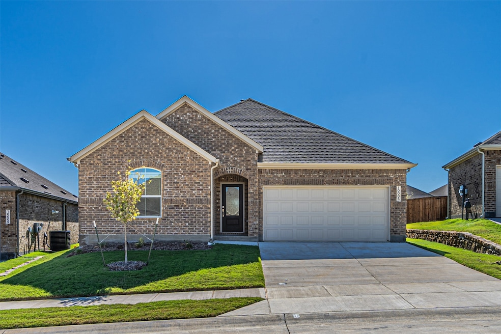 View of front of house featuring brick siding, a front yard, driveway, a garage, and roof with shingles