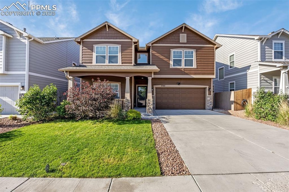 Craftsman-style house featuring stone siding, a garage, concrete driveway, and covered porch