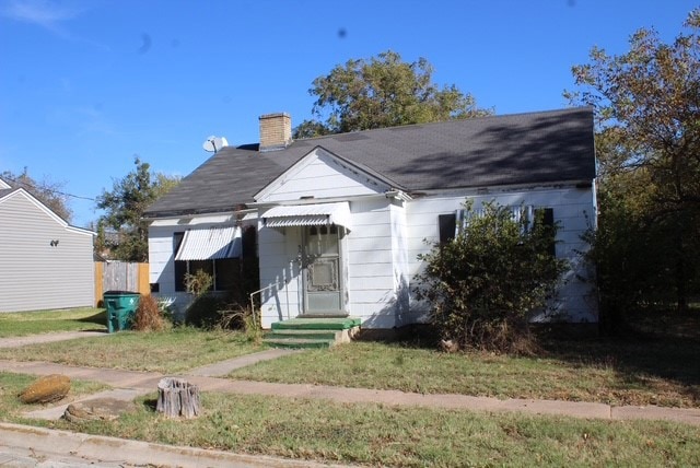 View of front facade with a chimney and a front lawn
