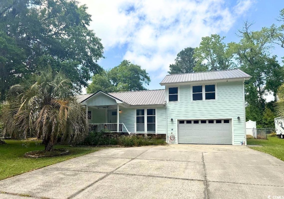 View of front of property with a garage, driveway, covered porch, and metal roof