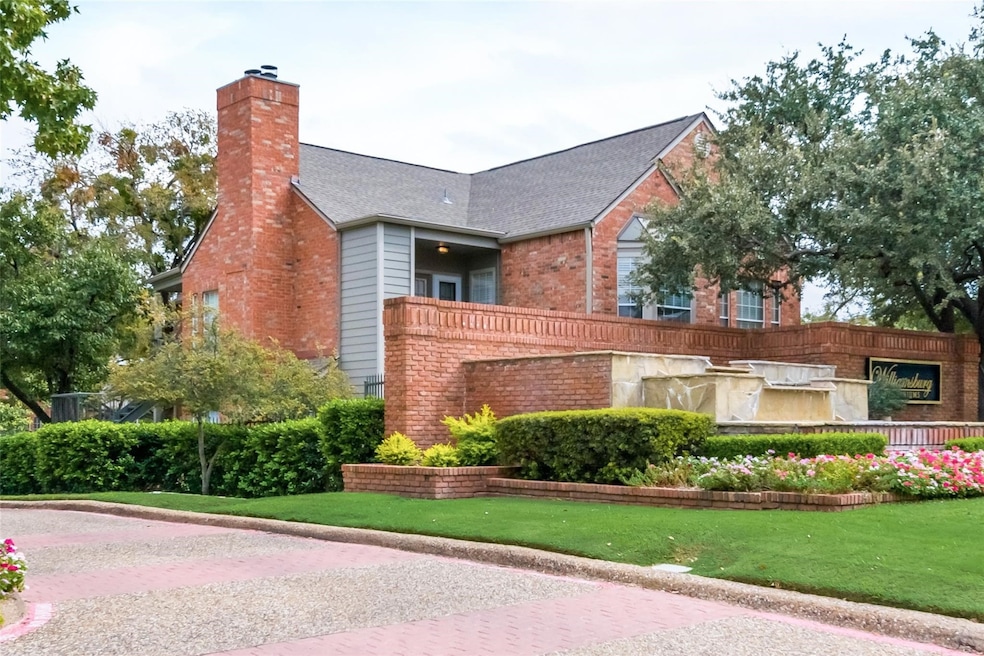 View of front of house featuring brick siding, a chimney, roof with shingles, a balcony, and a front lawn