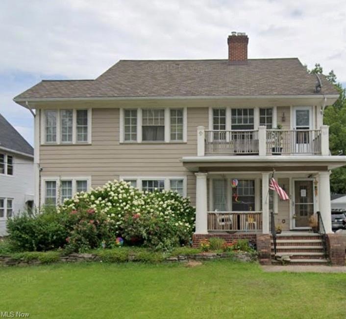 Colonial-style house featuring balcony and a front yard