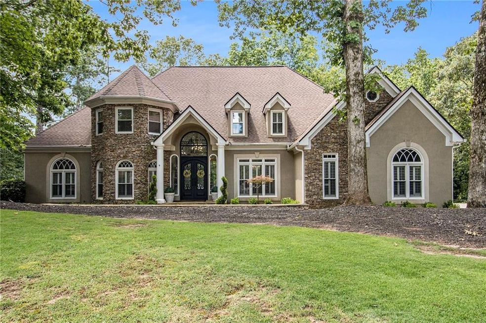 View of front of property with stone siding, stucco siding, a front yard, and french doors