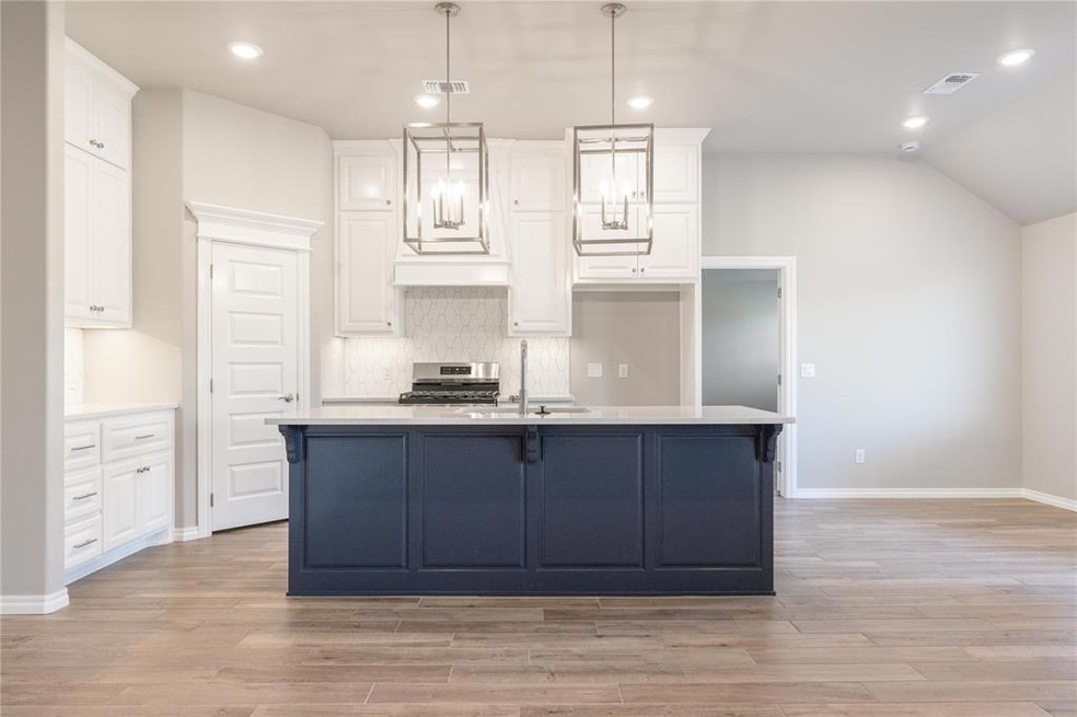 Kitchen featuring hanging light fixtures, white cabinetry, tasteful backsplash, recessed lighting, and a breakfast bar