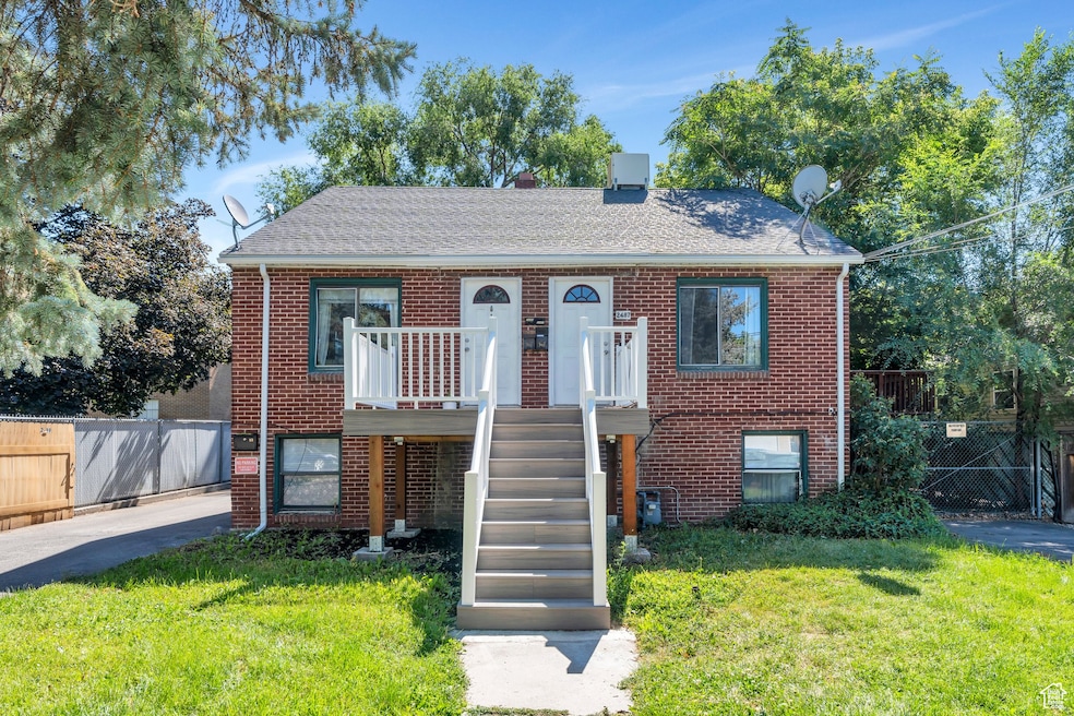 View of front of property featuring brick siding, roof with shingles, and stairs