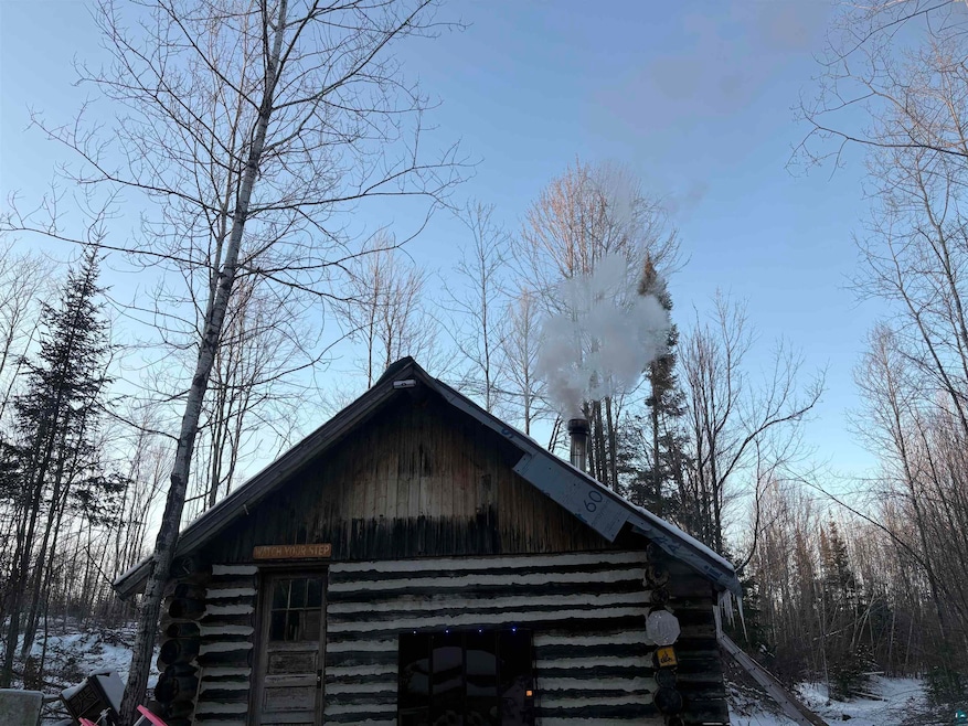 View of snow covered exterior with log exterior, a barn, and an outdoor structure