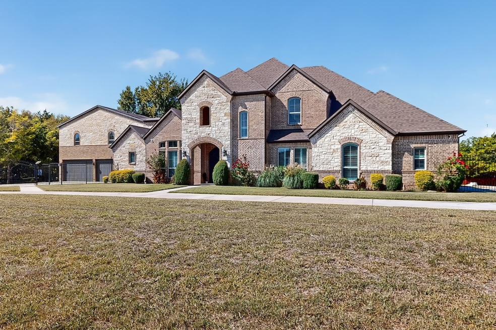 French country home with stone siding, a front yard, brick siding, and a shingled roof