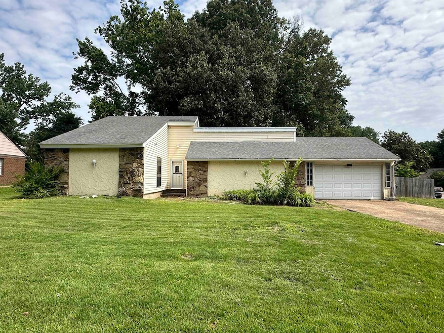 Mid-century home with stone siding, concrete driveway, and an attached garage