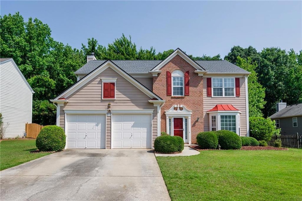 Colonial inspired home featuring driveway, brick siding, an attached garage, and a chimney