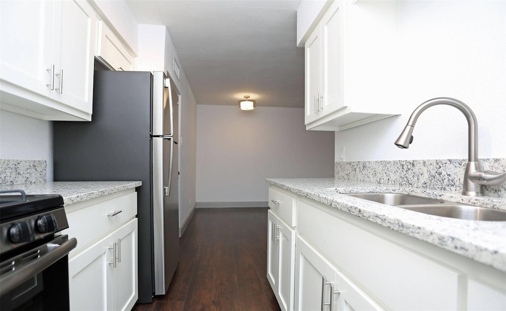 Kitchen featuring light stone countertops, dark ha