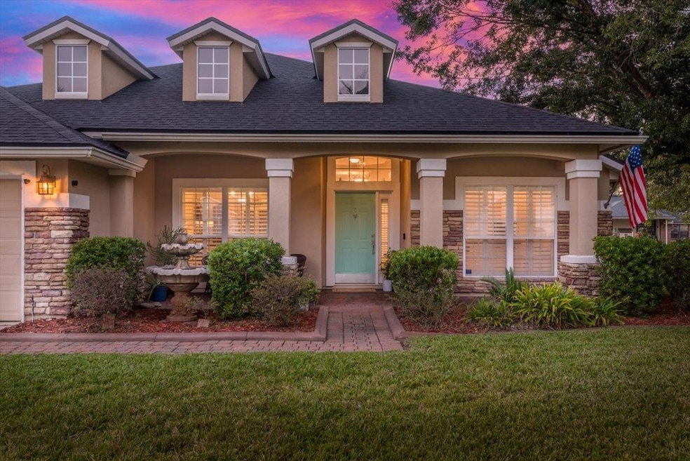View of front of house featuring stone siding, stucco siding, a yard, and a porch