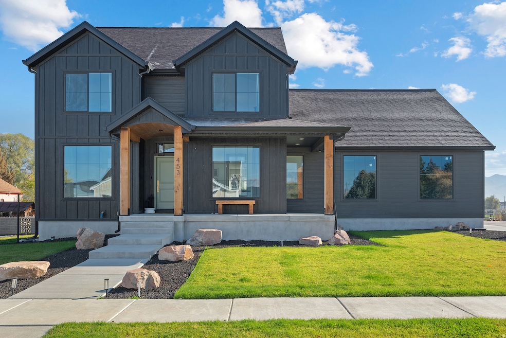 Modern farmhouse style home featuring board and batten siding, a shingled roof, and a front yard