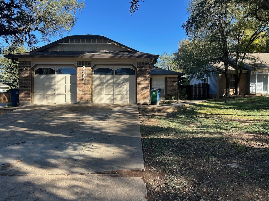 View of front facade featuring driveway, brick siding, and an attached garage