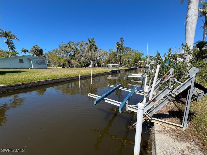 View of dock featuring a lawn, a water view, and b