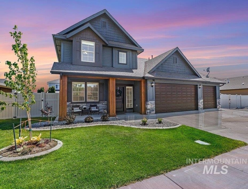 View of front of home featuring covered porch, driveway, an attached garage, and stone siding
