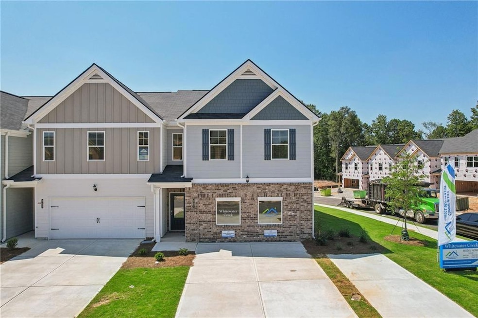 View of property with driveway, an attached garage, board and batten siding, brick siding, and a front yard