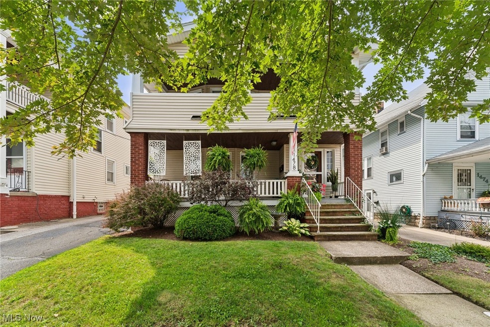 View of front of triplex featuring a manicured front yard and covered porch